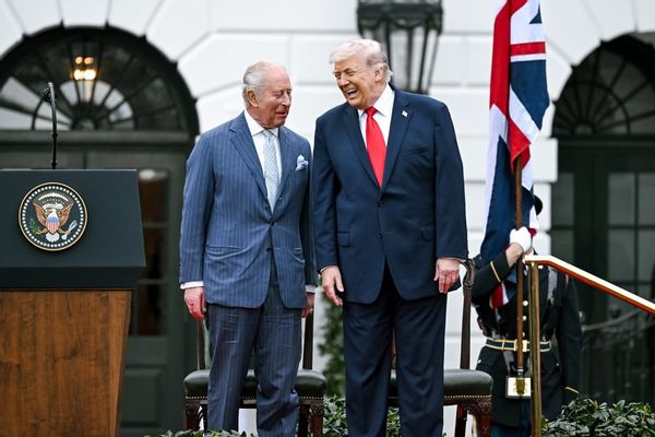 U.S. President Donald Trump and King Charles III stand together laughing. 