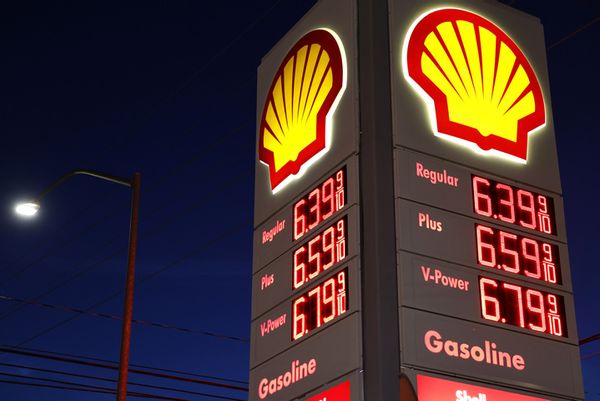 A large Shell gas station sign at night advertises gas prices over $6. 