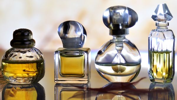 Four perfume bottles of varying sizes and shapes sit atop what appears to be a table.