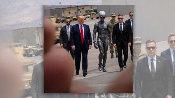 A white man walks in a group of people either wearing suits or military uniforms. Next to him is a large blue-grey alien.