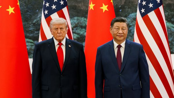U.S. President Donald Trump stands next to Chinese President Xi Jinping in front of U.S. and China flags. 