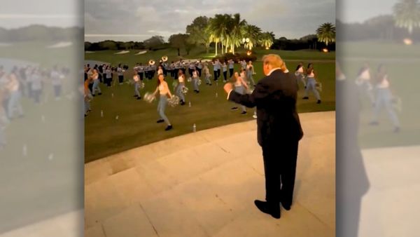 An image shows a screenshot from a video of US President Donald Trump dancing while watching and listening to a high school band and cheerleaders perform ahead of a Super Bowl in 2024 at Trump International Golf Club in West Palm Beach, Florida.