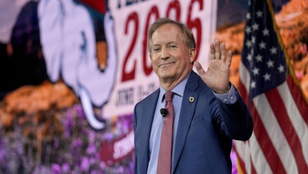 Ken Paxton, an older white man wearing a suit, waves. 
