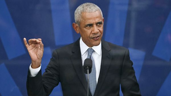 Former President Barack Obama stands in front of a podium. 