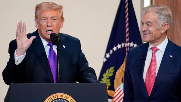 U.S. President Donald Trump stands behind a podium and speaks as Dr. Mehmet Oz, administrator for the Centers for Medicare & Medicaid Services, watches.