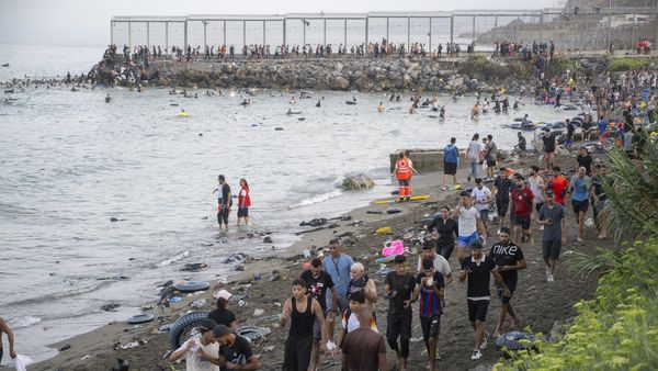 Migrants walk along the beach after crossing through the sea from Morocco into the Spanish territory of Cueta on July 30, 2026.