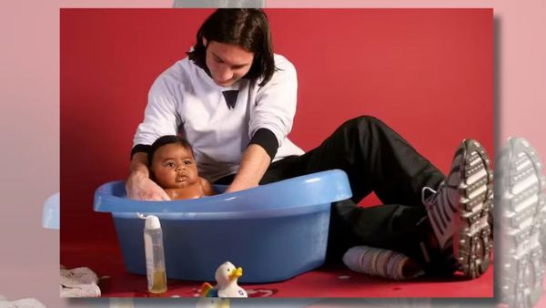 Young Lionel Messi, wearing a white shirt and black pants, bathes a baby Lamine Yamal in a small blue bathtub.