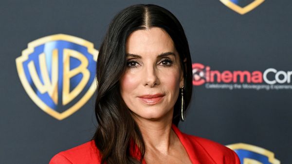 Sandra Bullock, a middle-aged woman with long brunette hair in a red suit. 
