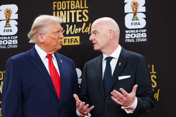 Two old white men wearing suits gesture as they talk to each other. Trump, on the left has medium length blond-to-white hair, while Infantino, on the right, is bald. 