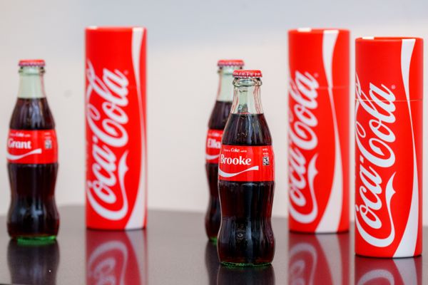 Three glass bottles of the Coca-Cola soft drink customized with the names Grant, Brooke and Ella on their red labels.