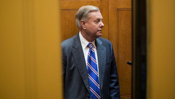 Lindsey Graham, an older white man in a suit, stands in an elevator with the doors half-open. 