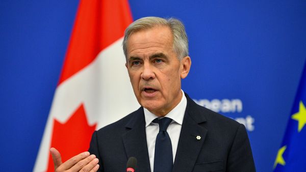Image shows Canadian Prime Minister Mark Carney in a black suit, speaking at an event.