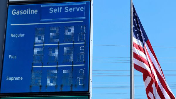 A blue gas price sign that says regular gas costs $6.29 alongside a large U.S. flag. 