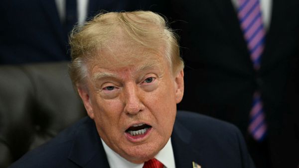  U.S. President Donald Trump speaks while wearing a dark suit jacket, white dress shirt and red tie.